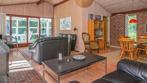 A spacious living room with a fireplace, leather sofa, dining table, and a brick wall. - 6 Person Holiday Home in Orsted-by Traum (Ørsted)