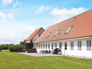 A building with a red-tiled roof, multiple windows, and a grassy courtyard. - 20 Person Holiday Home in Nordborg-by Traum (Nordborg)