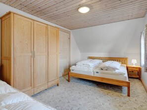 A bedroom with a wooden wardrobe, a bed with white bedding, a nightstand, and a ceiling light. - 20 Person Holiday Home in Nordborg-by Traum (Nordborg)