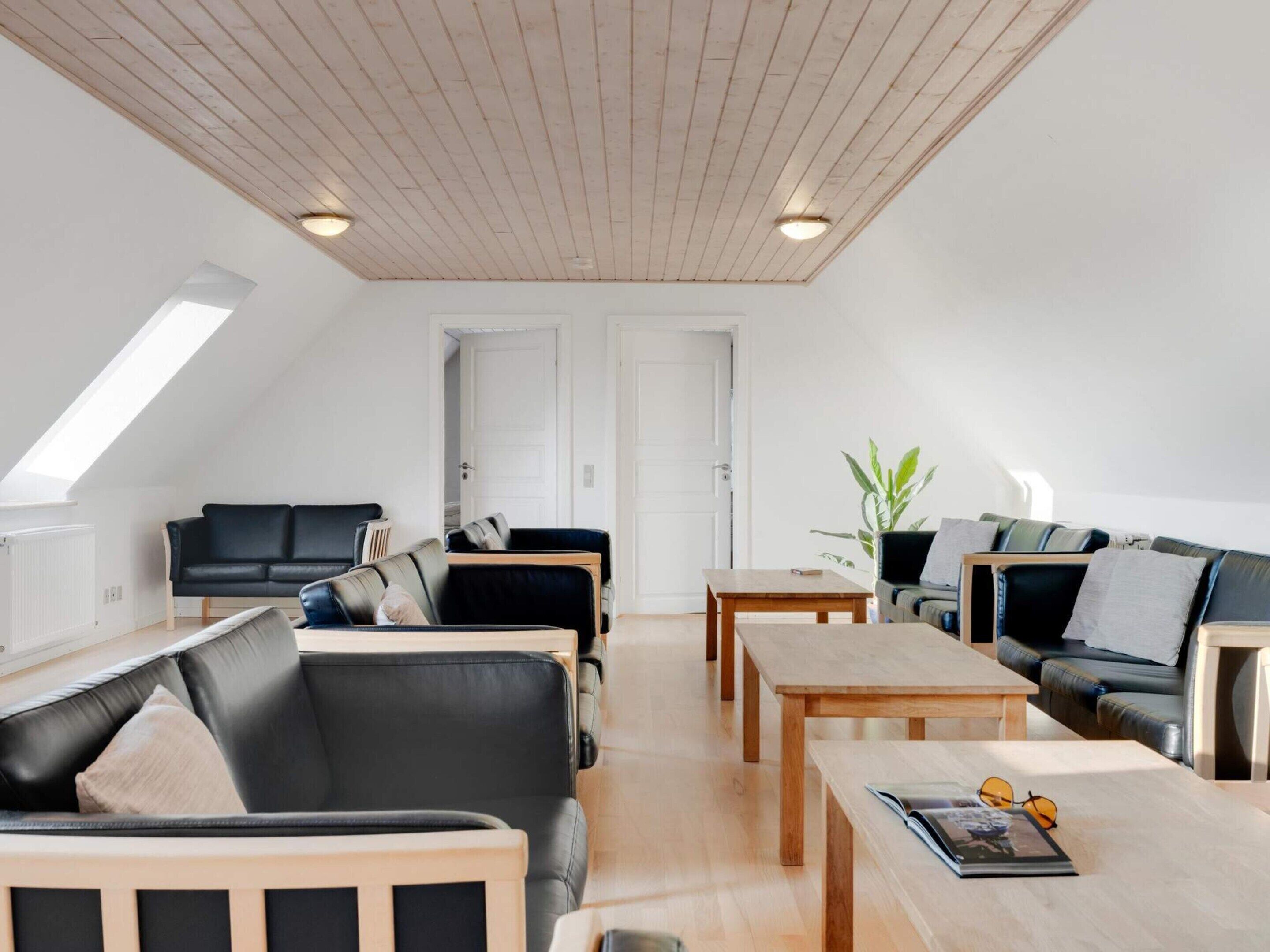 A modern loft-style living room with a sloped ceiling, built-in seating, and a large window providing natural light.