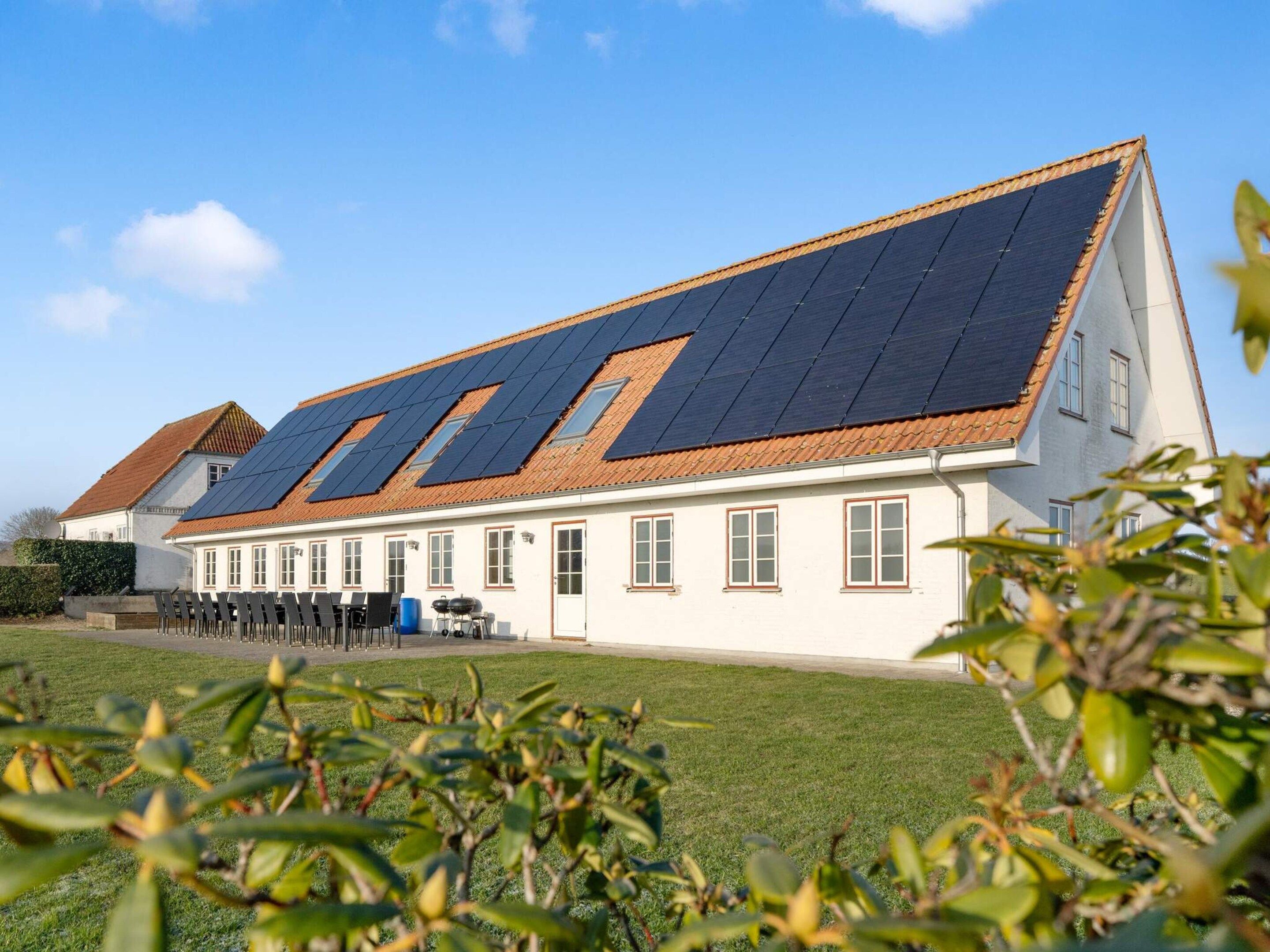 A building with a sloped roof, multiple windows, and a solar panel array.