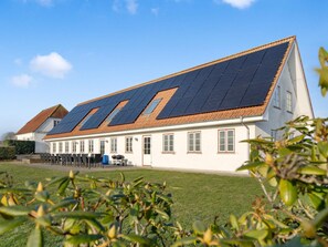 Un bâtiment doté d’un toit en pente, de nombreuses fenêtres et d’une installation de panneaux solaires.