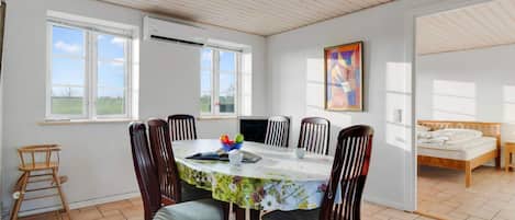 A dining area with a round table, six chairs, and a window.