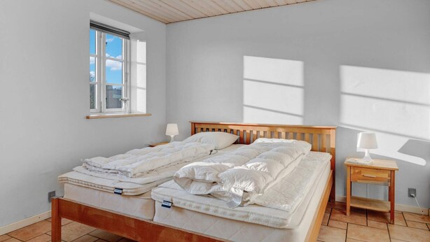 Una camera da letto con un letto di legno, due comodini, una finestra e vista sul cielo.