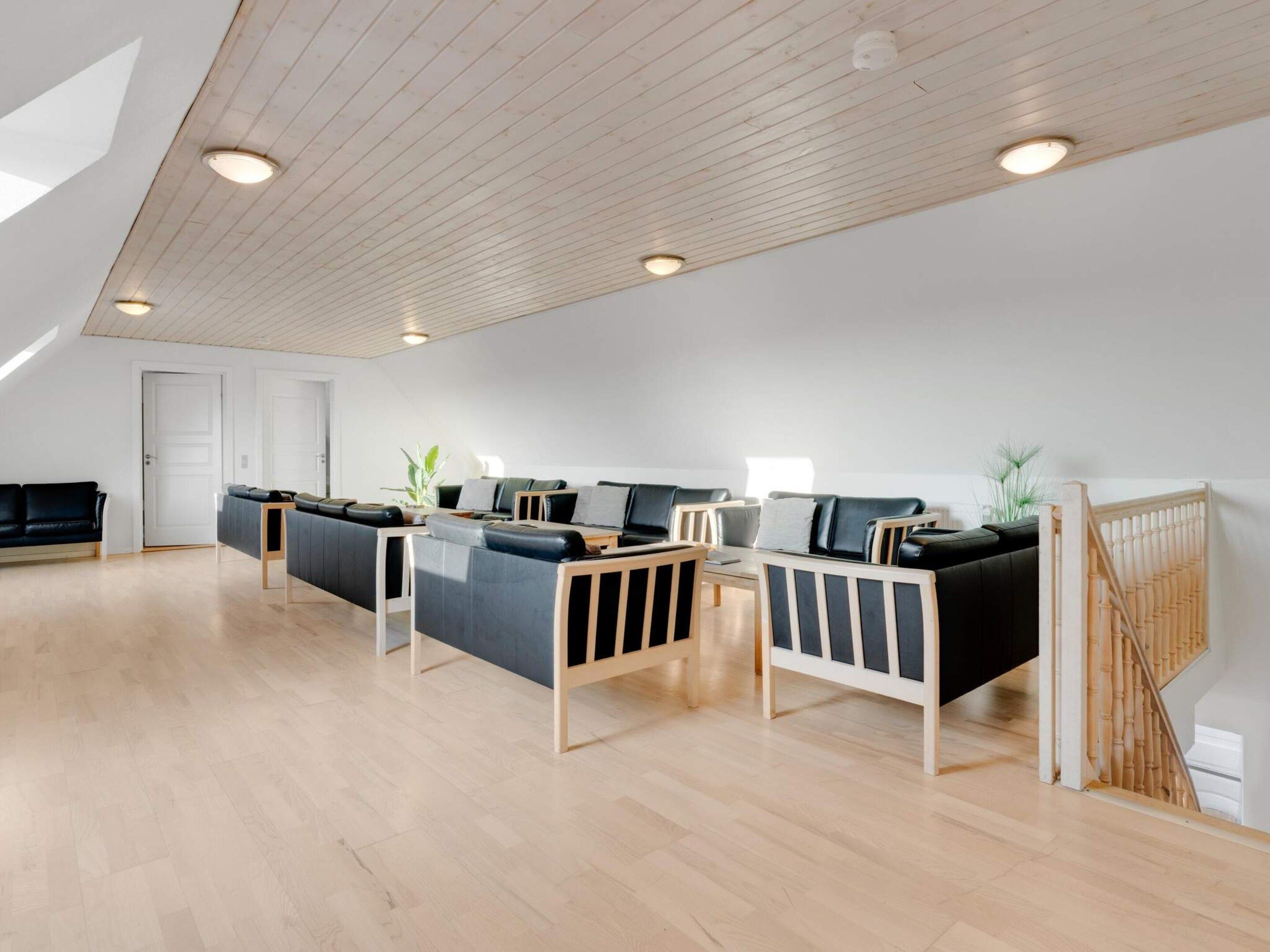 En rummelig opholdsstue med højt til loftet, trægulv og et moderne møbelarrangement.
