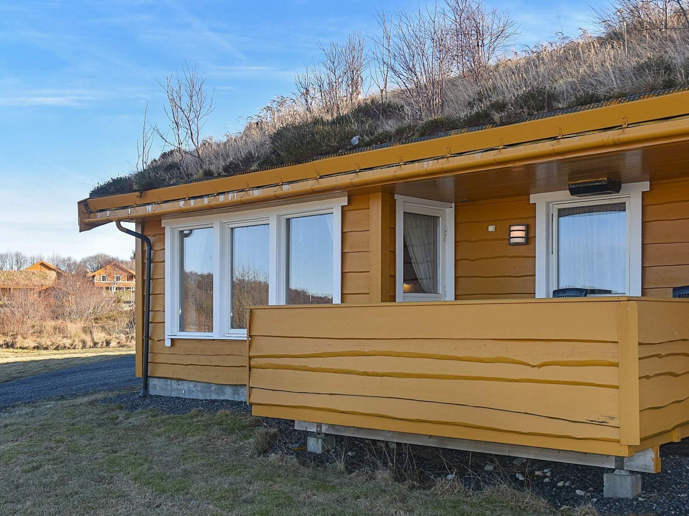 A yellow wooden building with a flat roof, multiple windows, and a small balcony.