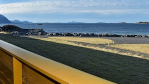 A coastal view with a rocky shoreline, a grassy area, and a clear sky.