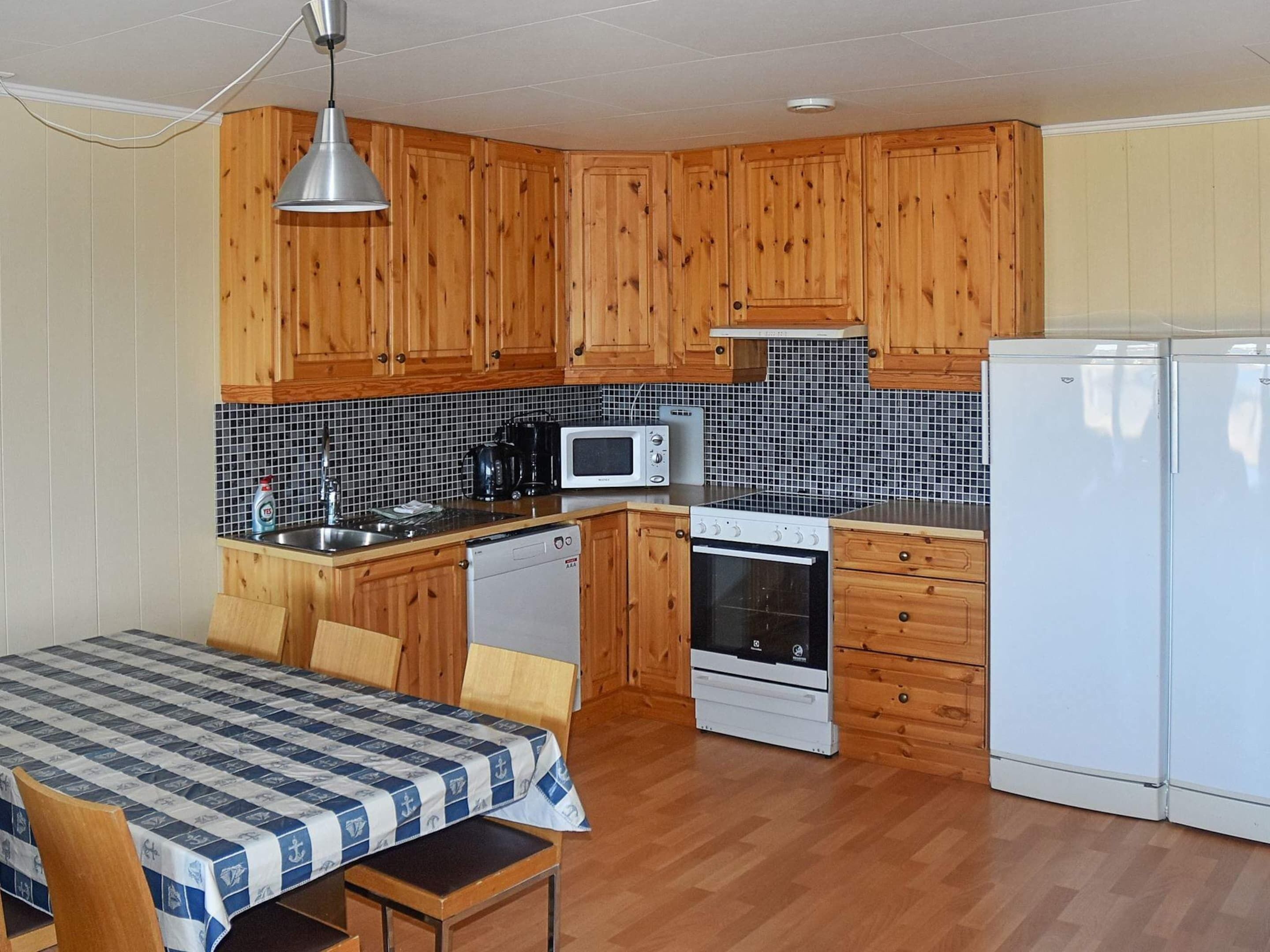Cocina compacta con armarios de madera, un microondas, estufa y refrigerador.