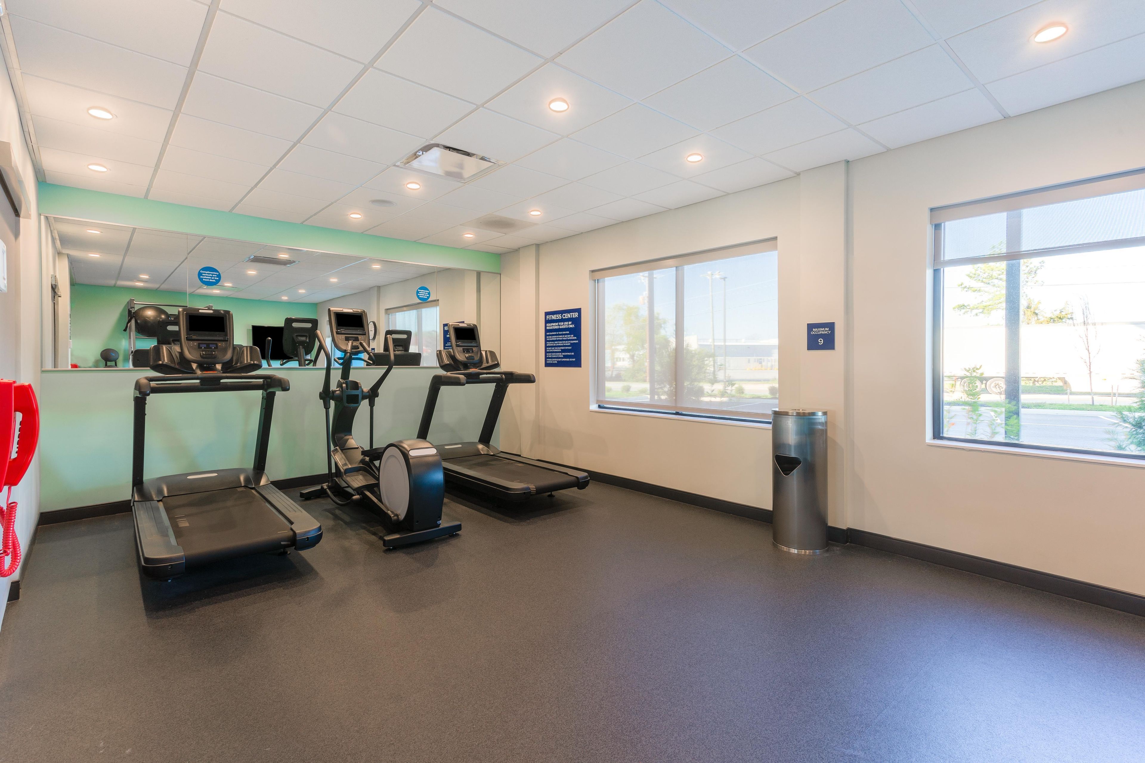 A fitness center with treadmills, exercise balls, and a trash can.