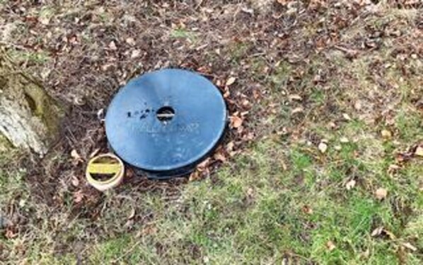 A blue circular object on the ground with a hole in the center, surrounded by grass and fallen leaves. - 6 Person Holiday Home in Gedser-by Traum (Gedser)