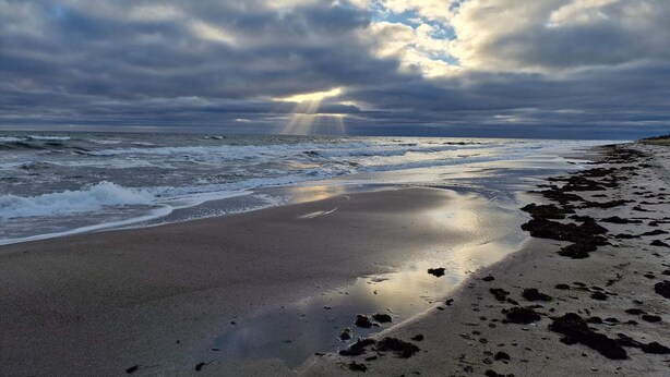 A beach with waves, a cloudy sky, and sunlight breaking through. - 6 Person Holiday Home in Gedser-by Traum (Gedser)