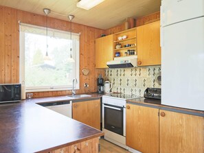 A kitchen with wooden cabinets, a Bosch oven, a refrigerator, and a window with a view of greenery. - 6 Person Holiday Home in Gedser-by Traum (Gedser)
