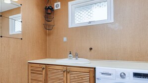 A compact bathroom with a wooden vanity, a washing machine, and a window with a view of a brick wall. - 6 Person Holiday Home in Gedser-by Traum (Gedser)