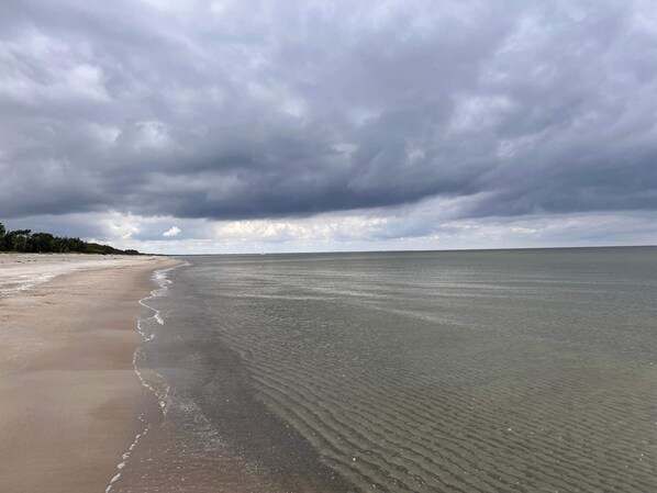 A beach with a wide sandy shore and calm water.