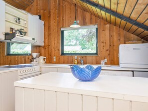 A kitchen with wooden walls, a white countertop, a blue decorative bowl, a coffee maker, and a dishwasher.
