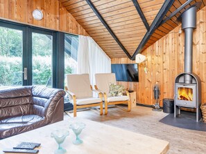A cozy room with a leather sofa, two chairs, a table with glasses, and a wood-burning stove.