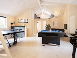 Une pièce équipée d’une table de billard, d’une table de snooker et d’une table de ping-pong. Un escalier y mène à un niveau supérieur.