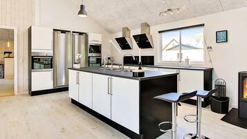 A modern kitchen with a central island, stainless steel appliances, and a large window providing natural light.