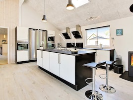 A modern kitchen with a central island, stainless steel appliances, and a large window providing natural light.