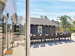 Eine Terrasse mit Sitzgelegenheiten, ein Gebäude mit Ziegeldach und Blick auf die Umgebung.