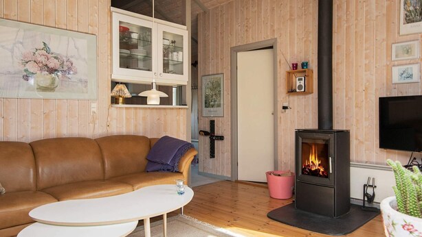 Una sala de estar acogedora con un sofá de cuero marrón, una mesa de centro blanca, chimenea y paneles de madera.