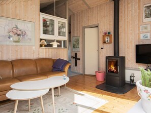 A cozy living room with a brown leather sofa, a white coffee table, a fireplace, and wooden paneling. - 4 Person Holiday Home in Oksbol-by Traum (Oksbol)