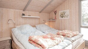Un dormitorio con techo de madera, una cama doble con dos almohadas, mesitas de noche y una ventana con vistas.