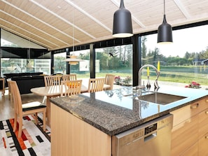 A modern kitchen with a large island, stainless steel appliances, and a view of the outdoors.