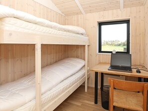 A bunk bed room with a desk and laptop, a window with a view, and a wicker chair. - 5 Star Holiday Home in Hjorring (Hjørring)