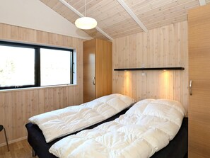 A room with a bed, a window, and wooden paneling.