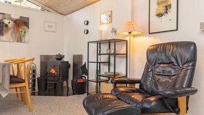 A cozy living room with a leather recliner, a wooden chair, a small table, a bookshelf, and a fireplace.