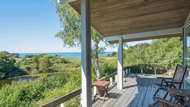 A wooden deck with outdoor furniture, overlooking a lush landscape and a body of water. - Fantastic Holiday Home in Knebel With Wifi (Knebel)