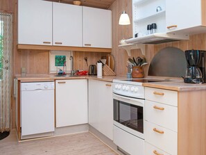 A compact kitchen with white cabinets, a Bosch dishwasher, a stove, and a coffee maker. - Fantastic Holiday Home in Knebel With Wifi (Knebel)