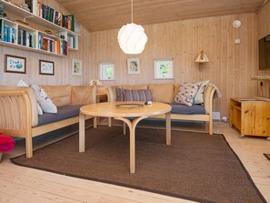 A cozy living room with a wooden floor, a round coffee table, a sofa set, a bookshelf, and framed pictures on the wall. - Fantastic Holiday Home in Knebel With Wifi (Knebel)