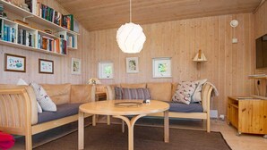A cozy living room with a wooden interior, a round table, and a bookshelf filled with books. - Fantastic Holiday Home in Knebel With Wifi (Knebel)