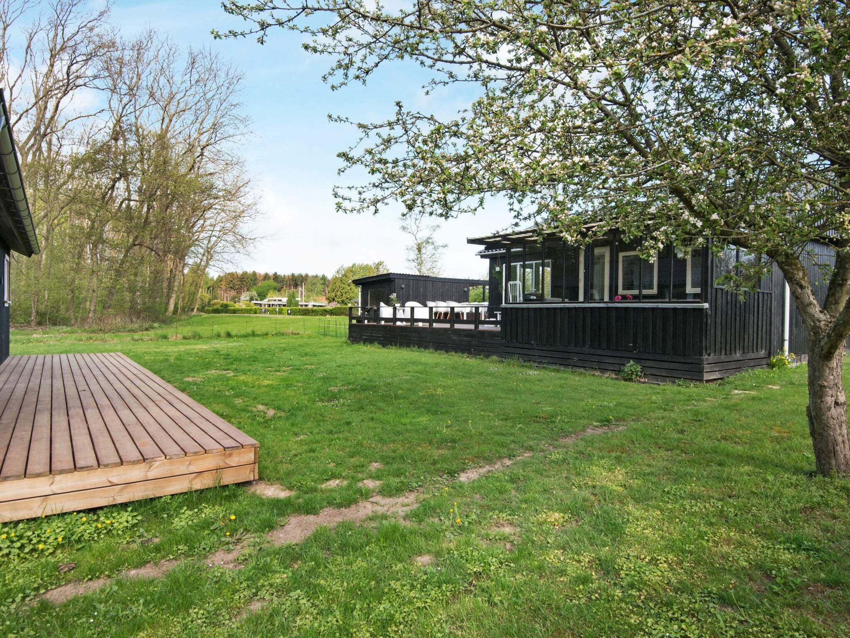 A wooden deck leading to a black cabin with a covered outdoor seating area.