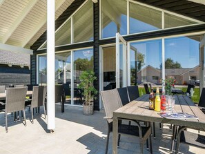 An outdoor patio with a table, chairs, and a bottle of beer. - Holiday Home in Kappeln (Kappeln)