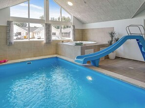 A swimming pool with a blue slide, a hot tub, and a view of houses outside. - Holiday Home in Kappeln (Kappeln)