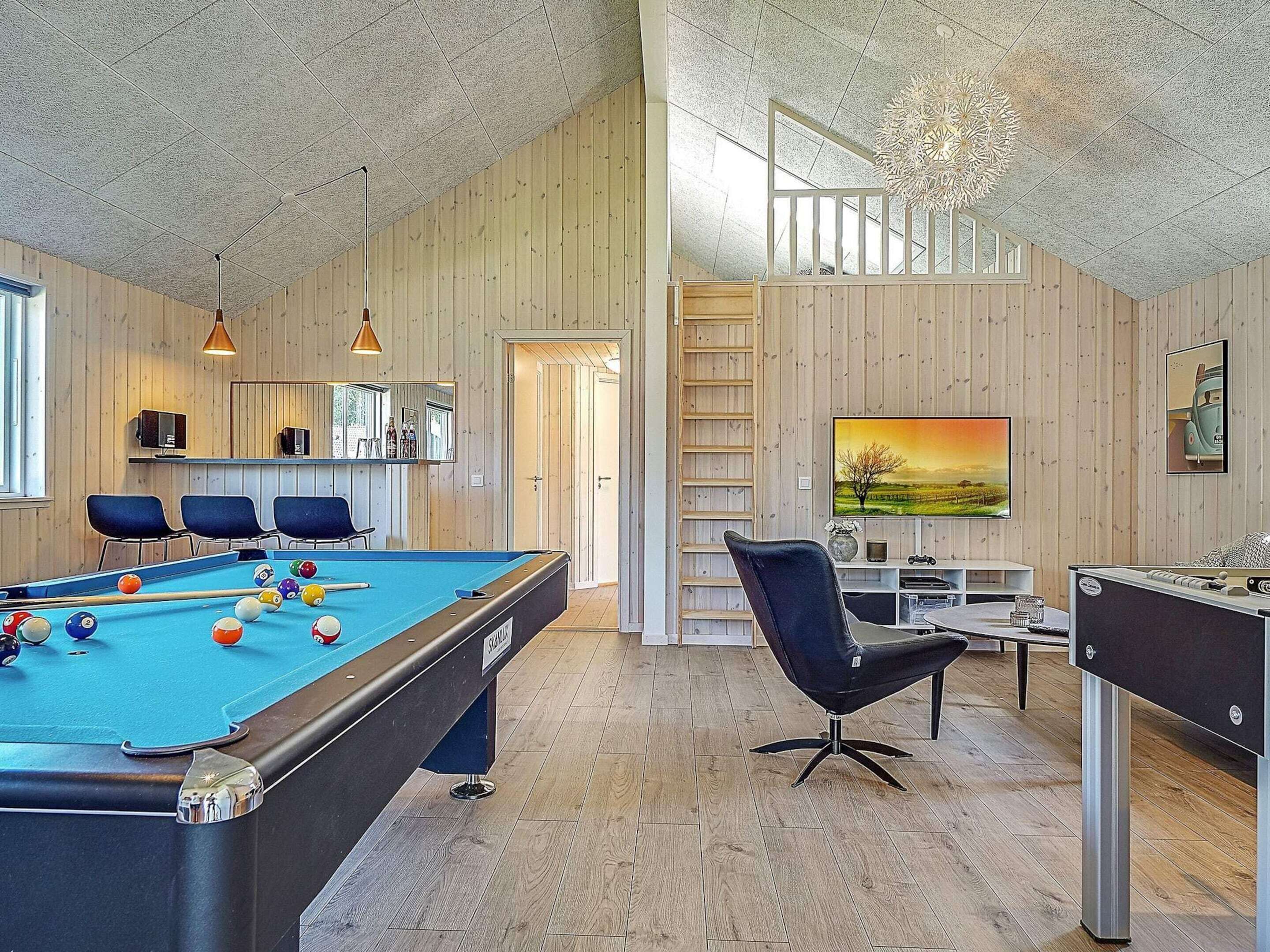 A pool table with balls, a pool table, a sofa, a TV, and a ladder.