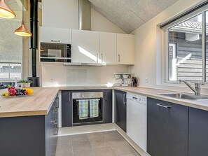 A compact kitchen with a dishwasher, oven, and a window with a view of the outside. - Holiday Home in Kappeln (Kappeln)
