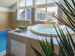 A hot tub in a room with a view of houses, a window, and a tiled floor. - Holiday Home in Kappeln (Kappeln)