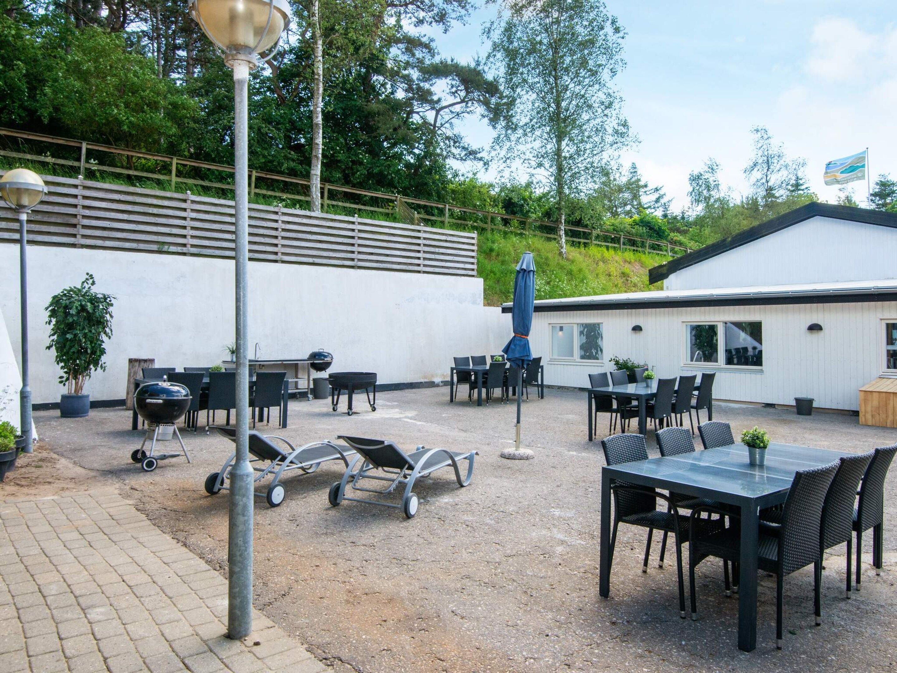 An outdoor patio area with tables and chairs, a barbecue grill, and a lamp post.