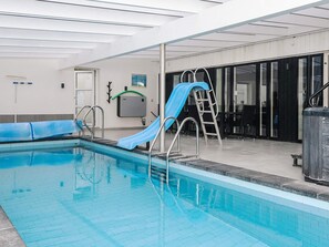 An indoor swimming pool with a blue slide and a ladder. - 36 Person Holiday Home in Ebeltoft-by Traum (Ebeltoft)