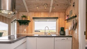 Een moderne keuken met houten lambrisering, een groot raam en een vaatwasser.
