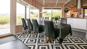 Een moderne eethoek met een grote tafel, zwarte stoelen en een vloerkleed met een patroon.
