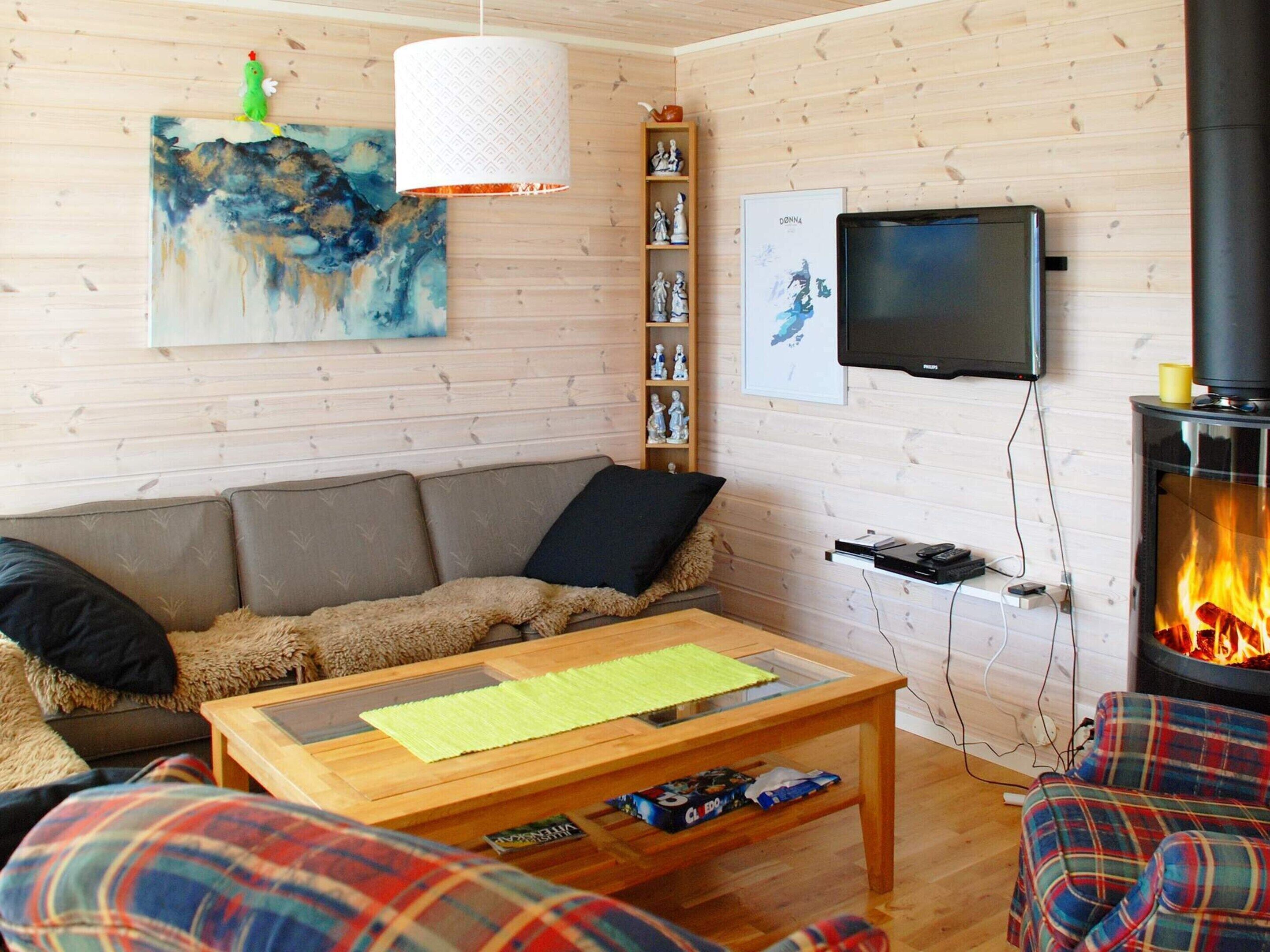 A cozy living room with a sofa, a coffee table, a fireplace, a television, and a painting on the wall.