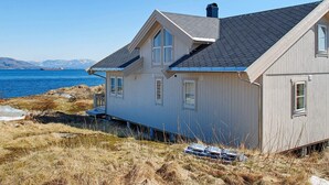 A coastal house with a sloped roof, large windows, and a view of the sea. - Holiday Home in DÃ¸nna (Dønna)