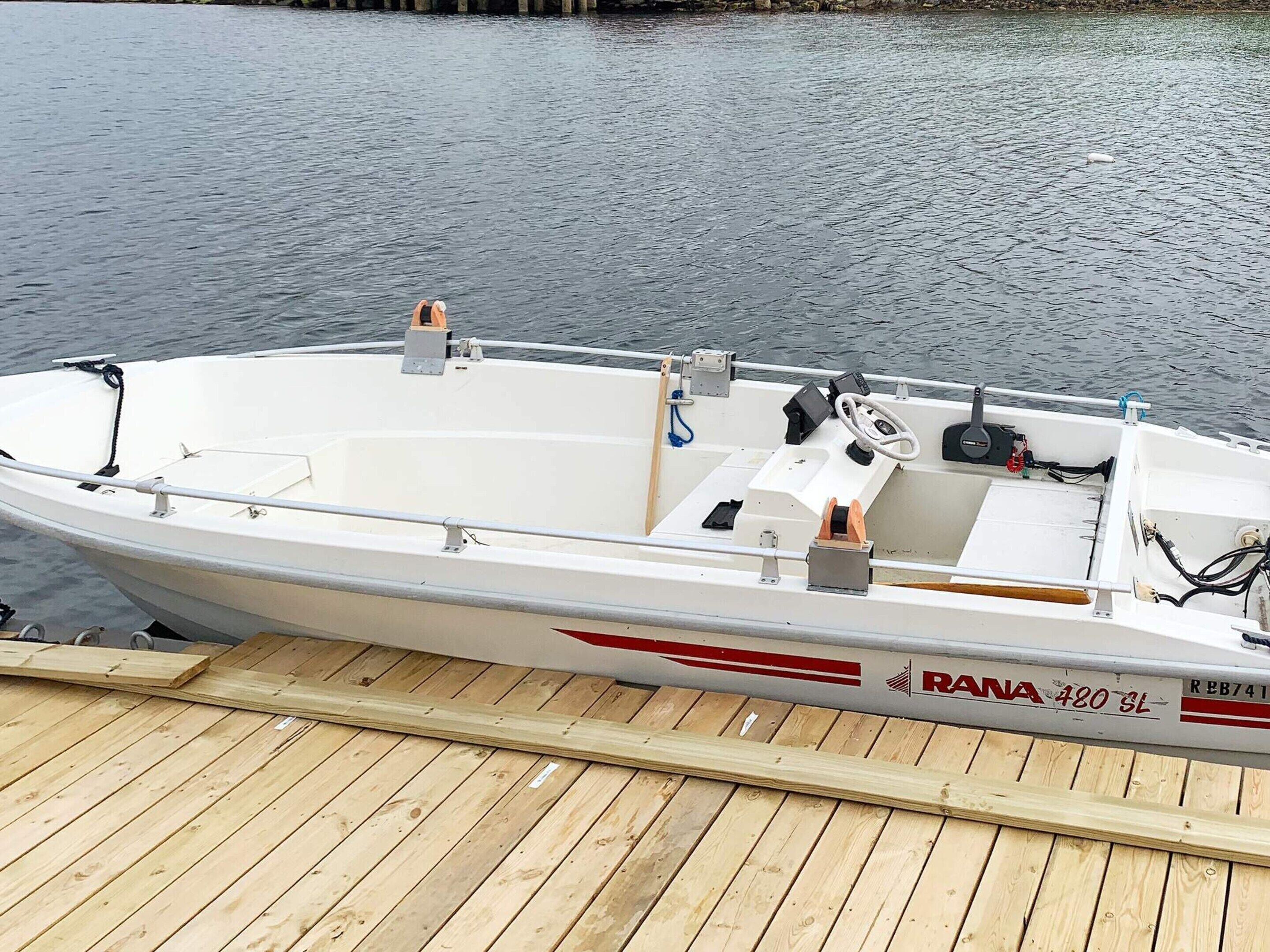 A white motorboat with a cabin, a steering wheel, and a motor on the dock.