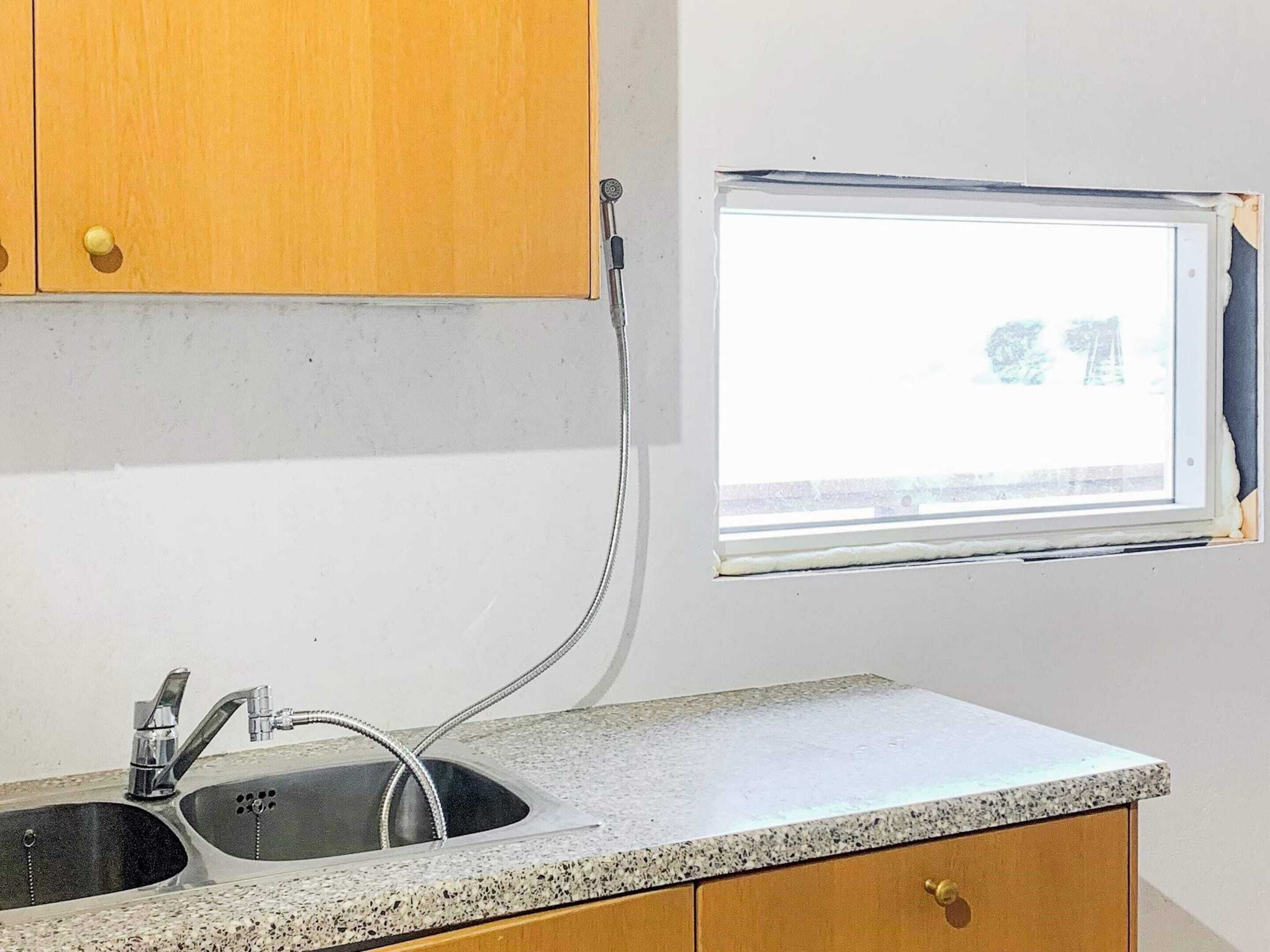 Uma cozinha com pia, torneira e janela.