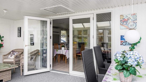 A dining area with a table set for two, wicker chairs, and a potted plant. - Simplistic Holiday Home in Ringkøbing near Sea (Ringkobing)